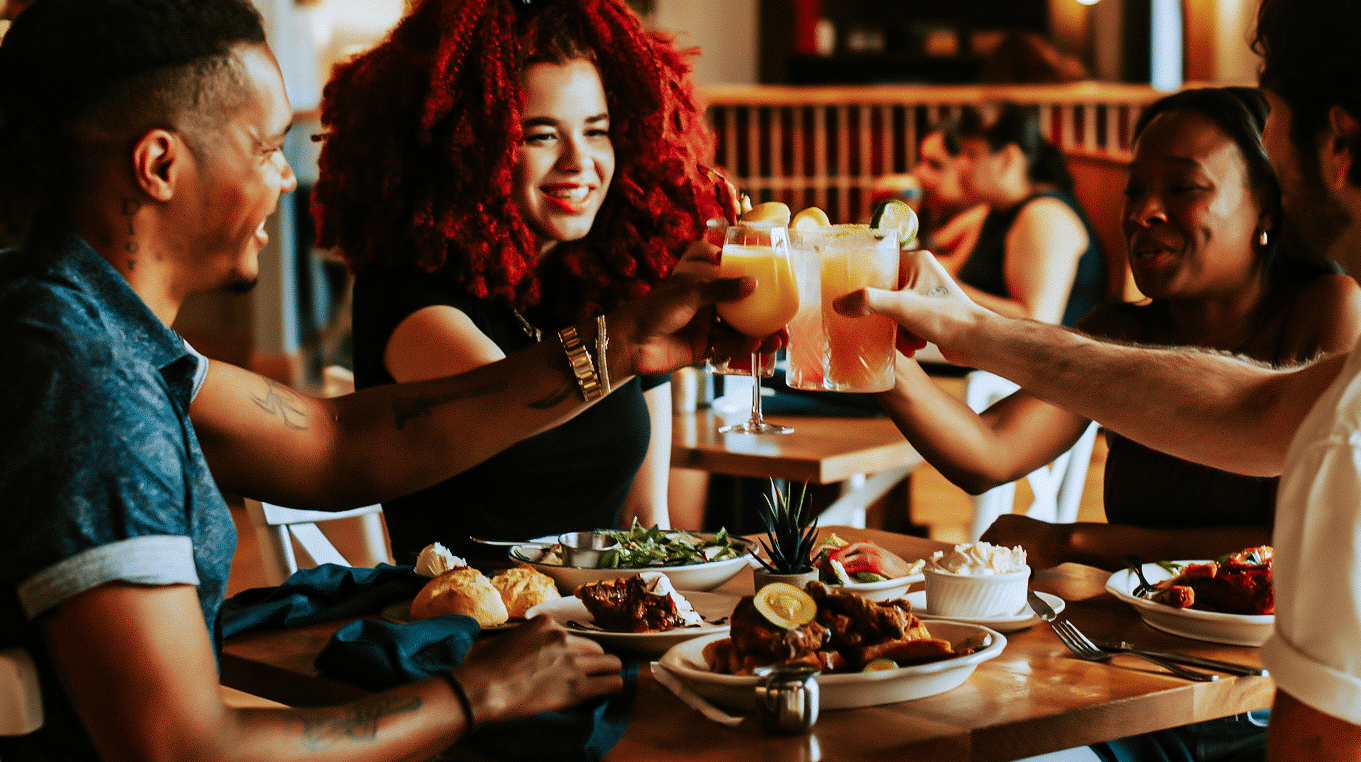 Guests toast at Tupelo Honey’s bar — craft cocktails, local beers, and lively Happy Hour energy.